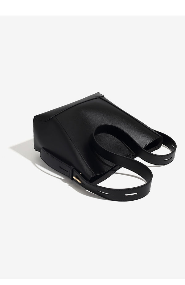 Structured smooth leather-look bucket shoulder bag with long adjustable strap and gold-tone buckle hardware in brown, detail