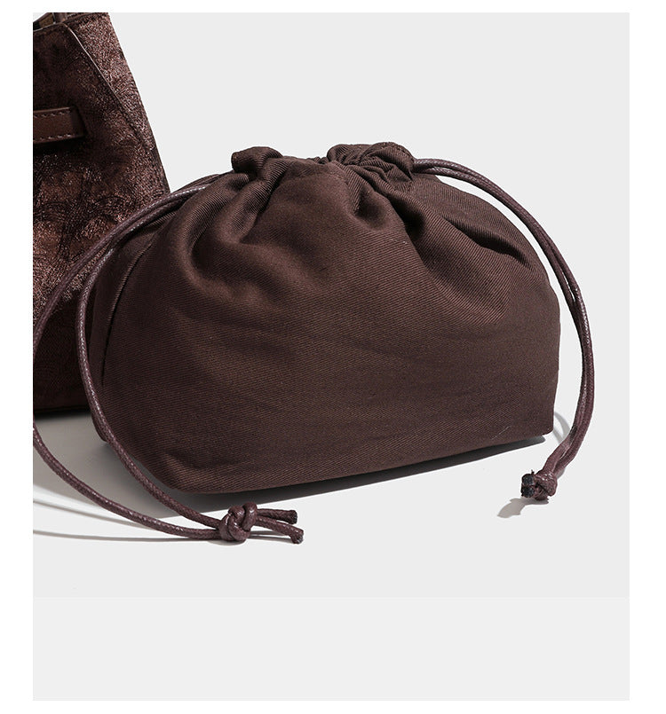 Small structured bucket satchel in embossed velvet-texture fabric with silver turn-lock hardware, rounded top handle, and