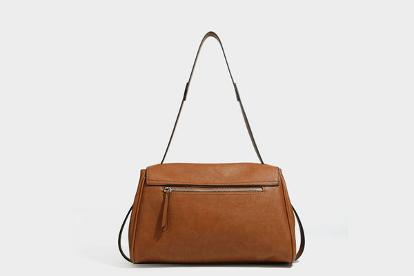 Strukturierte rechteckige dunkelbraune Schultertasche in Lederoptik mit Klappe, mehrlagigem Detail auf der Vorderseite und langem verstellbarem Riemen, Detailansicht