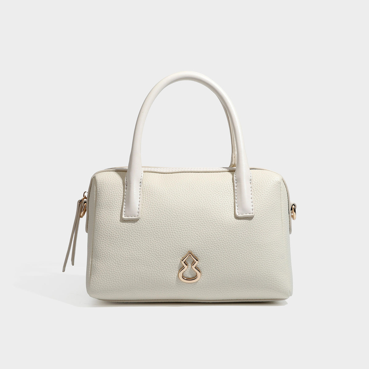Small structured pillow satchel bag with pebbled leather-look finish, dual rolled top handles, gold-tone gourd emblem, and
