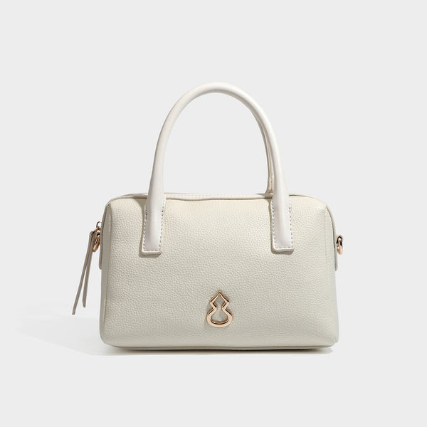 Small structured pillow satchel bag with pebbled leather-look finish, dual rolled top handles, gold-tone gourd emblem, and