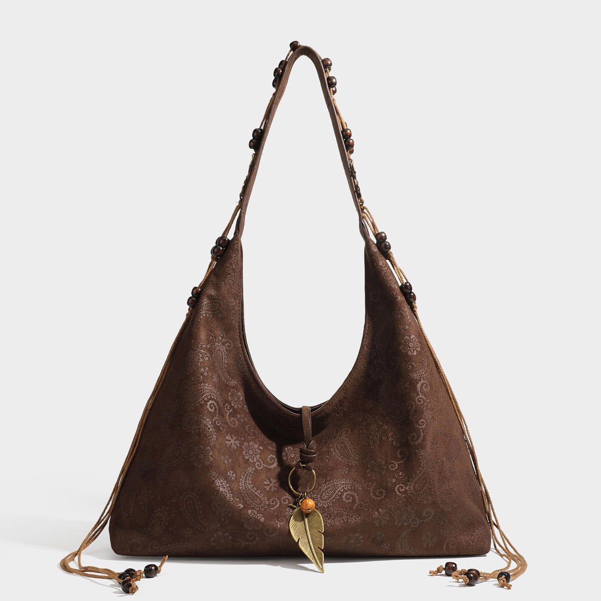 Slouchy boho hobo shoulder bag in embossed brown suede-look finish with beaded strap, cord tassels, and brass-tone leaf