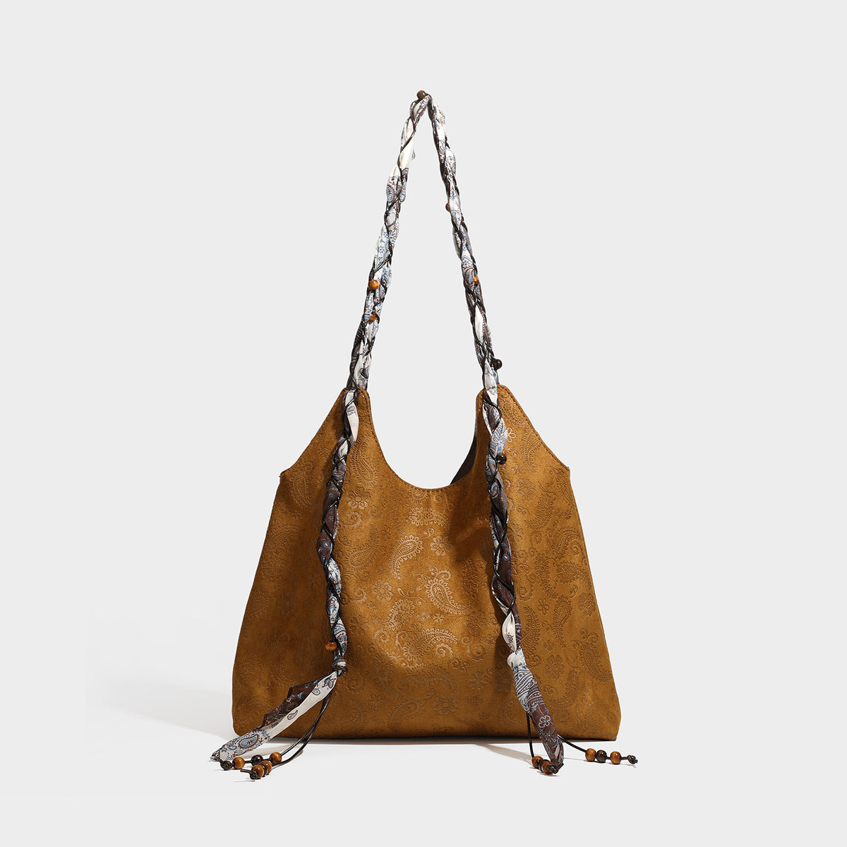 Slouchy paisley-embossed suede-look shoulder tote bag with braided patterned fabric straps and wood bead accents, detail view