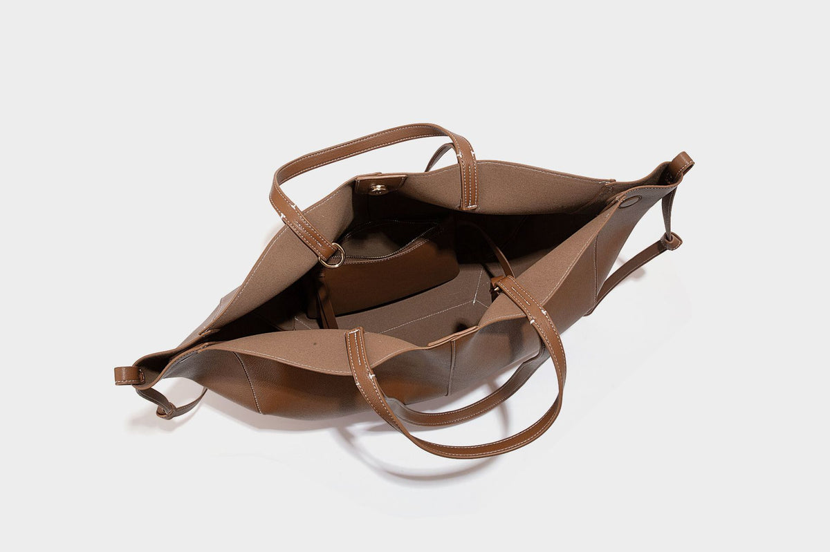 Große, formstabile trapezförmige Tote-Bag aus braunem Lederimitat mit genarbter Oberfläche, zwei Tragegriffen und seitlichen Bindebändern, Detail