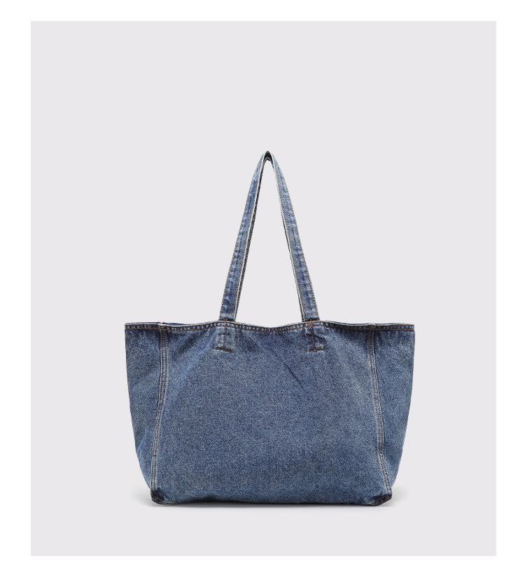 Große Tote-Bag aus verwaschenem blauem Denim mit handschriftlich wirkendem Grafikprint, kontrastierenden orangefarbenen Nähten und langem Stoff-Schulterriemen