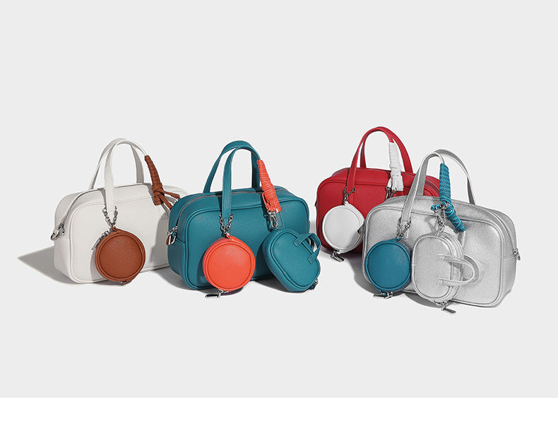 Structured pebbled leather-look Boston bowling bag in tan with blue detachable round mini pouch, dual top handles, and