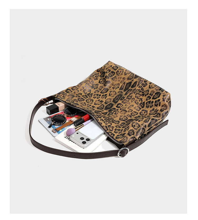 Slouchy leopard print hobo shoulder bag with glossy coated finish, top zipper closure, dark brown trim, and dangling charm