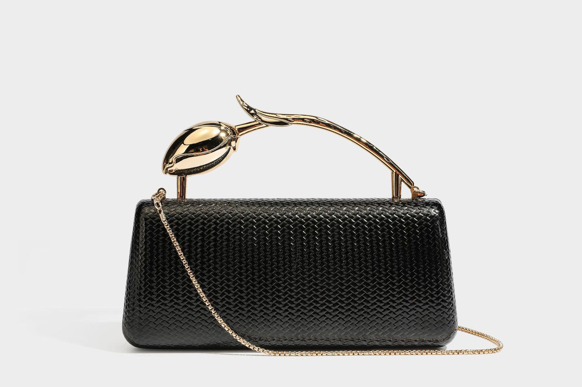 Structured rectangular metallic woven clutch bag with sculptural gold-tone leaf top handle and detachable chain strap, detail