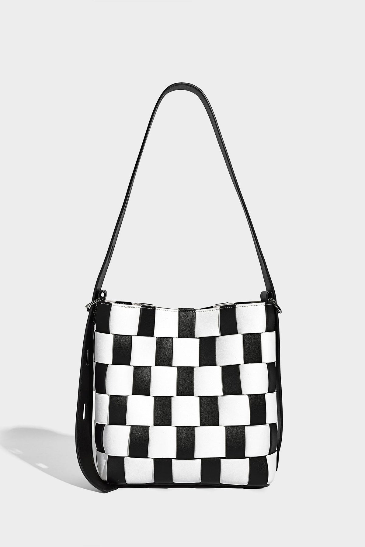 Hand-woven black-and-white checkerboard bucket bag with smooth black trim, silver-tone ring hardware, and adjustable