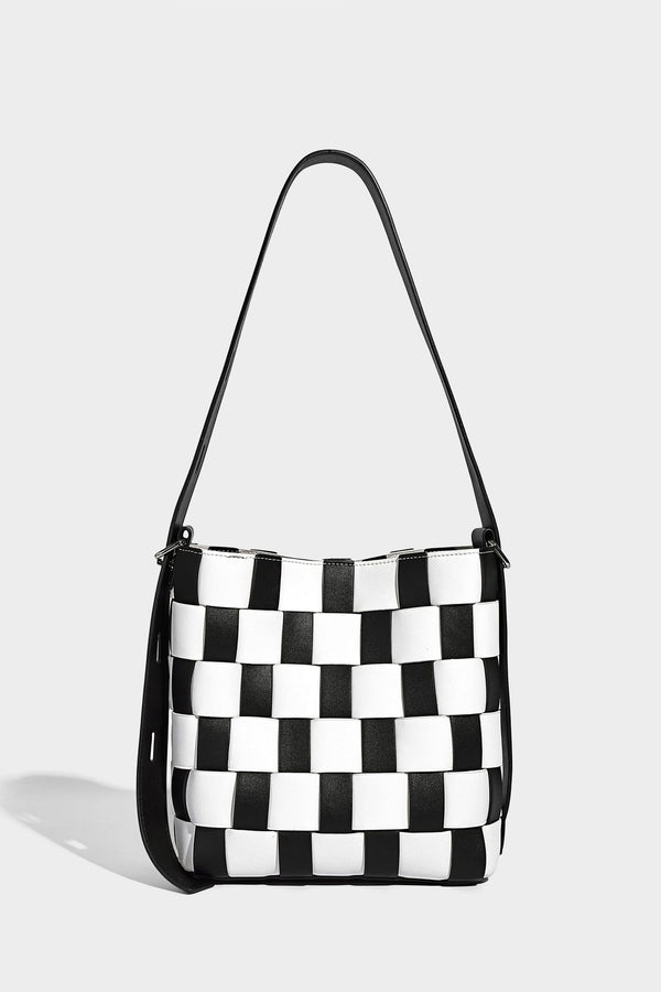 Hand-woven black-and-white checkerboard bucket bag with smooth black trim, silver-tone ring hardware, and adjustable