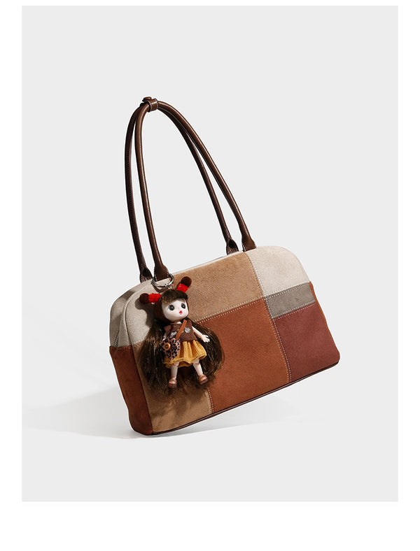 Boxy patchwork suede-look shoulder tote in tan, beige, rust, and brown panels with double brown straps and hanging doll