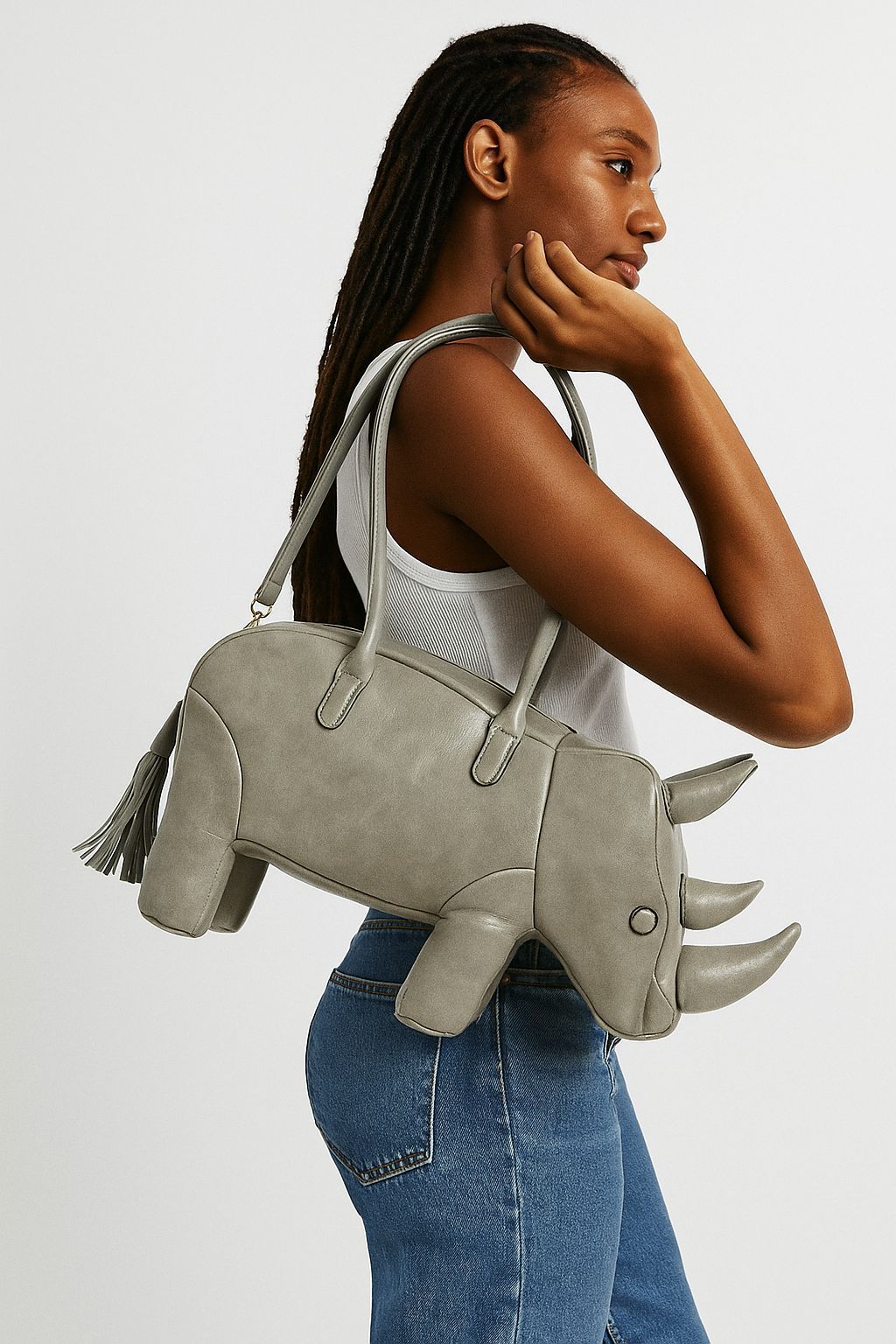 Rhinoceros-shaped 3D structured handbag with sculpted horns, four legs, tassel tail, twin top handles, and detachable, detail