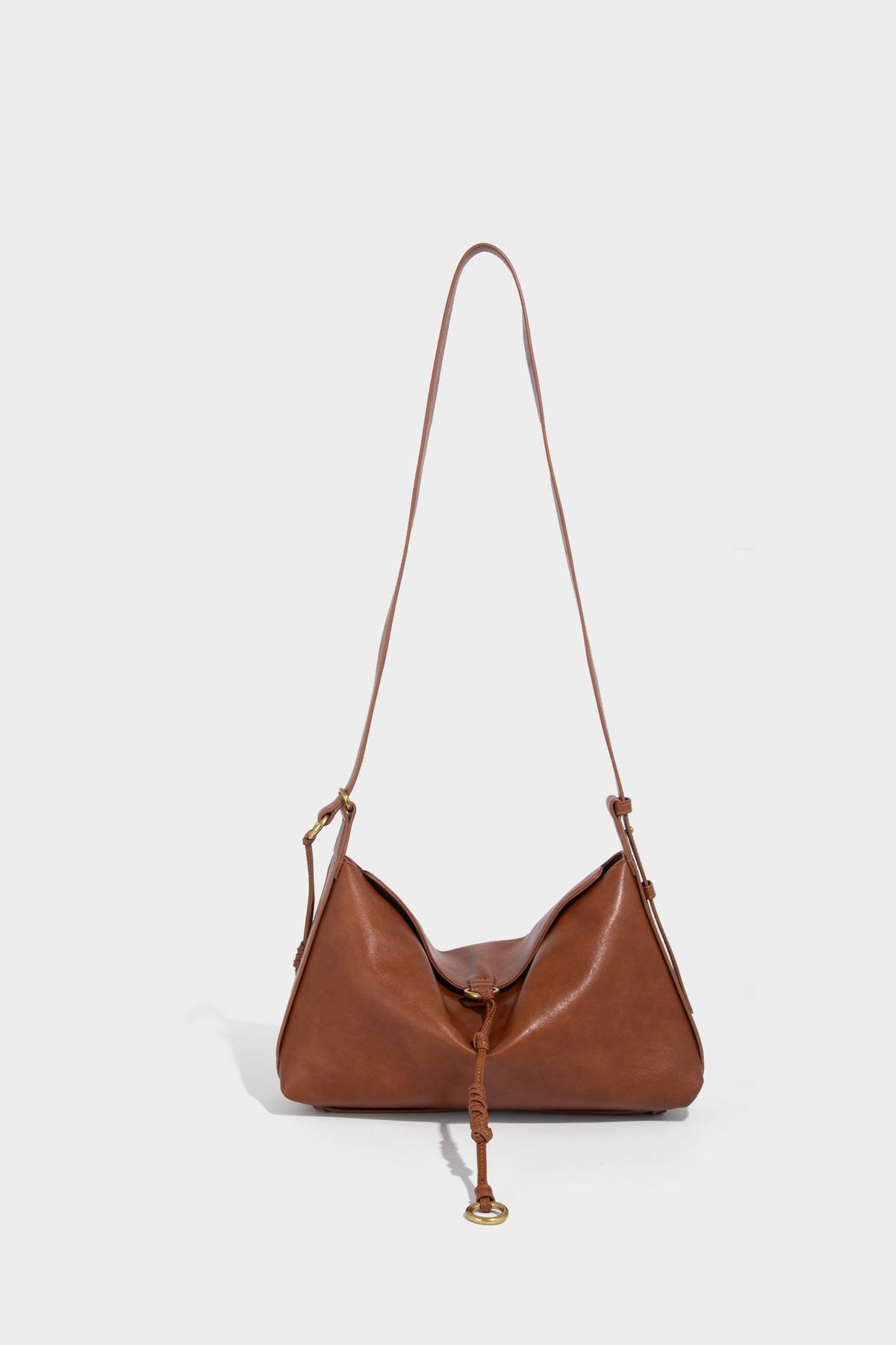 Slouchy brown leather-look shoulder bag with knotted drawcord tie closure, gold-tone ring hardware, and long adjustable
