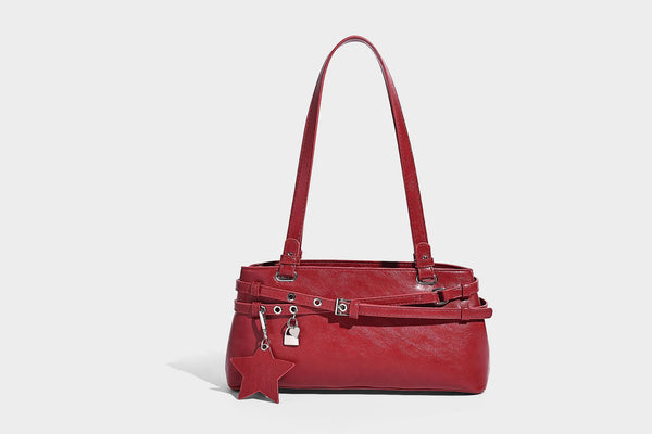 Structured glossy leather-look shoulder bag with wraparound belt straps, silver-tone hardware, and dangling star charm