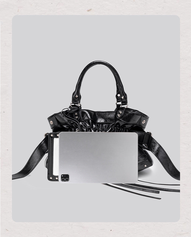 Black glossy ruched convertible tote bag with silver-tone rivets, detachable wide shoulder strap, external zip pouch, and