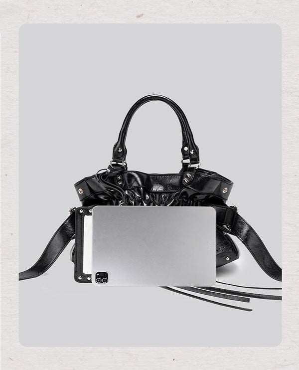 Black glossy ruched convertible tote bag with silver-tone rivets, detachable wide shoulder strap, external zip pouch, and