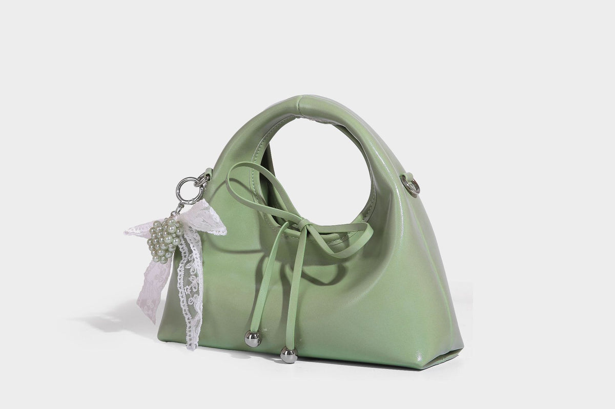 Kleine kuppelförmige Henkeltasche in glänzender Lederoptik mit Kordelzugverschluss, weißem Spitzen-Schleifenanhänger und silberfarbenen Metallbeschlägen