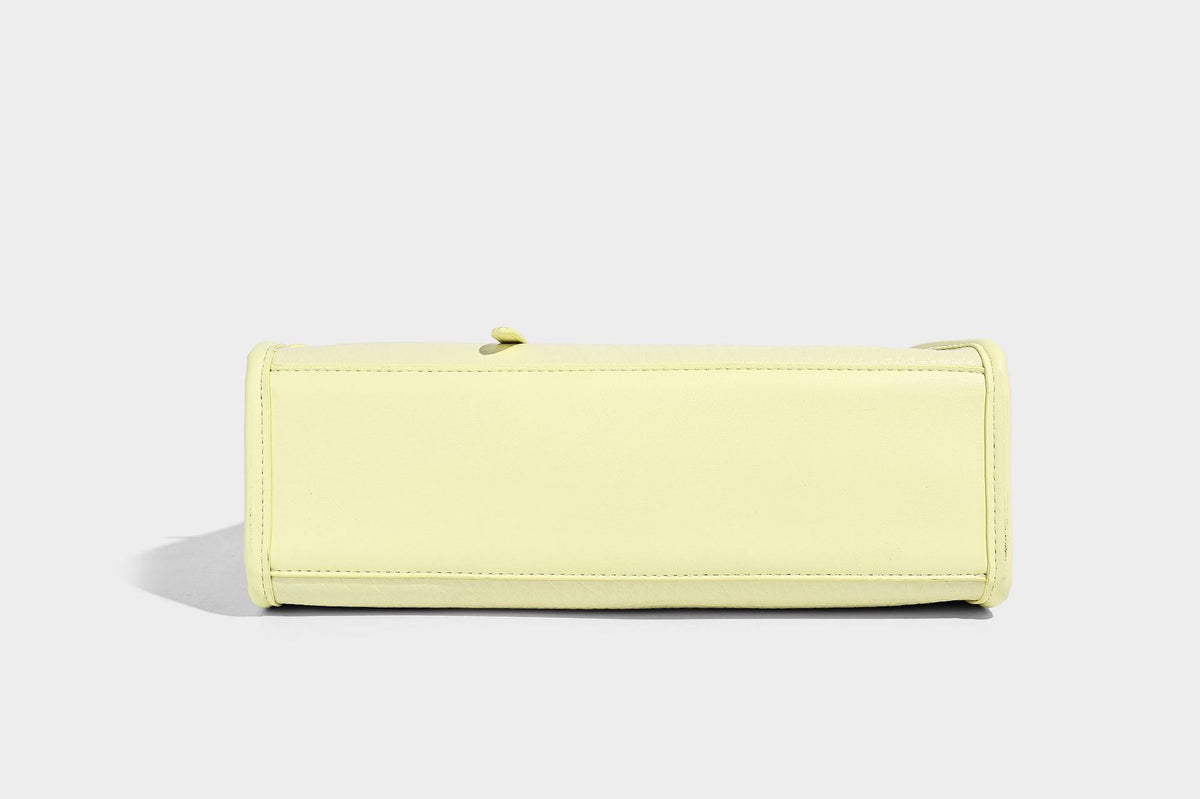 Structured trapezoid tote bag in pebbled leather-look finish with double top handles, silver-tone bar hardware, and, detail