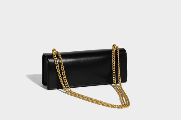 Structured rectangular crossbody bag with glossy finish, three vertical gold-tone embossed plaques, and gold chain strap