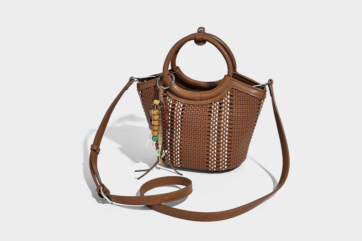 Kleine strukturierte Beuteltasche aus geflochtenem Material mit rundem Tragegriff in Lederoptik, silberfarbenen Beschlägen und perlenbesetztem Quastenanhänger, Detail