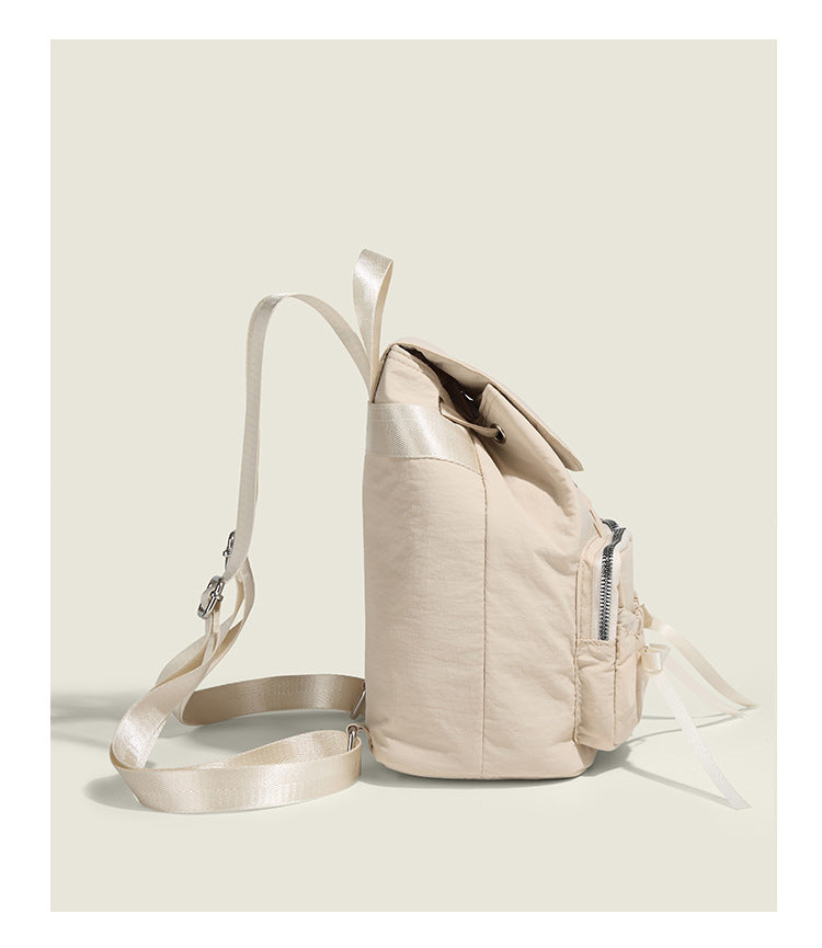 Soft matte nylon drawstring backpack with ruched bow-detail front zip pockets, top carry handle, and silver-tone hardware