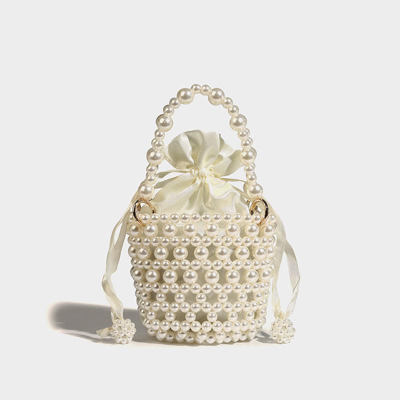 Ivory faux-pearl beaded mini bucket bag with satin drawstring interior, gold-tone ring hardware, arched pearl top handle