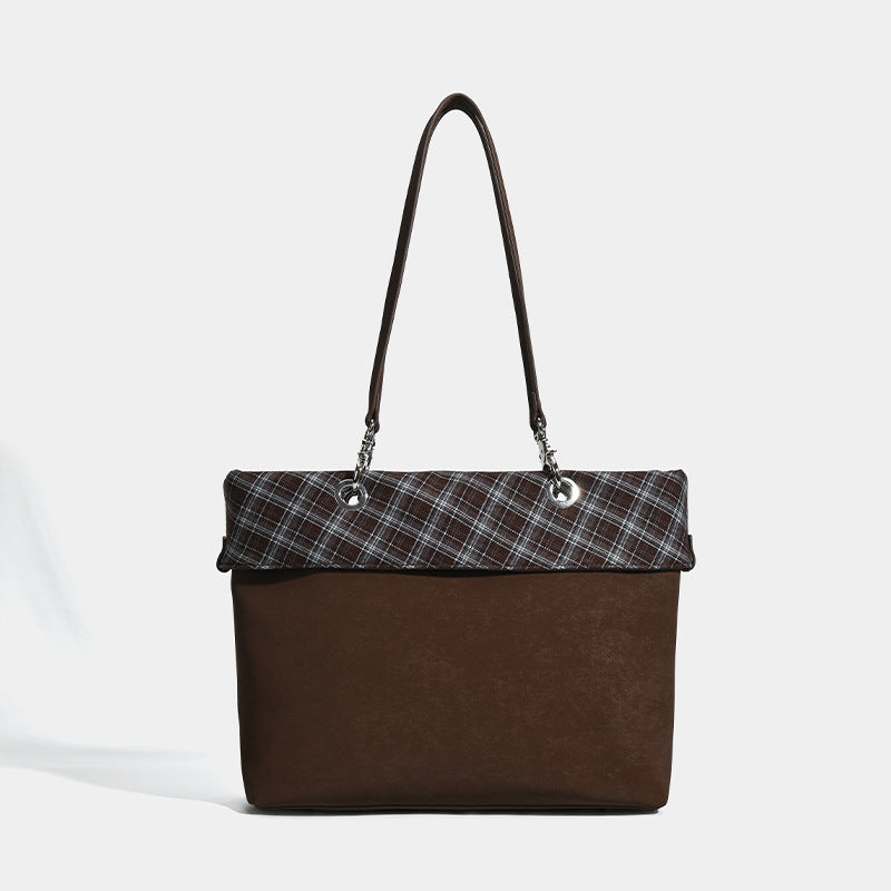Brown structured tote bag with woven plaid fold-over top panel, silver-tone ring hardware, and long flat shoulder straps