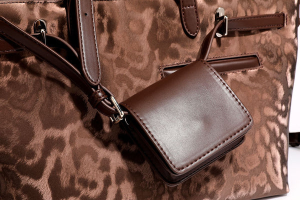 Glossy leopard-print tote bag with leather-look dark trim, dual top handles, detachable shoulder strap, and attached front