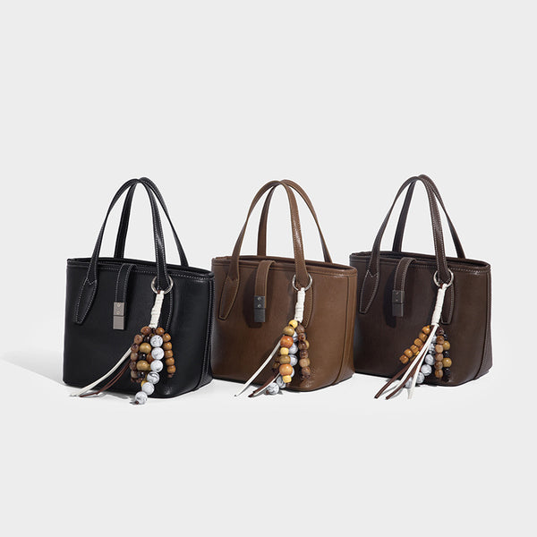 Compact structured bucket tote bag with pebbled textured finish, dual top handles, silver-tone lock hardware, and detachable