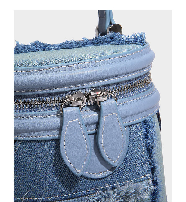 Mini cylindrical barrel bucket bag in denim patchwork with frayed edges, smooth leather-look trim, zip-around top closure