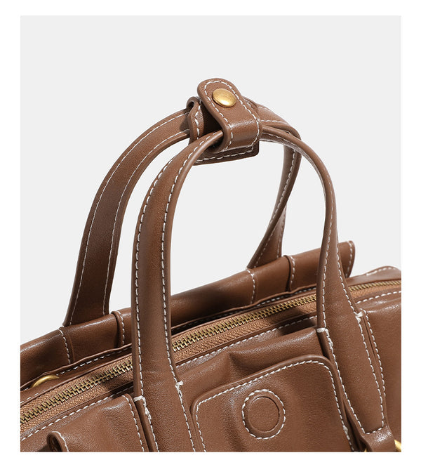 Compact structured satchel bag with dual top handles, gold-tone O-ring hardware, contrast topstitching, and detachable