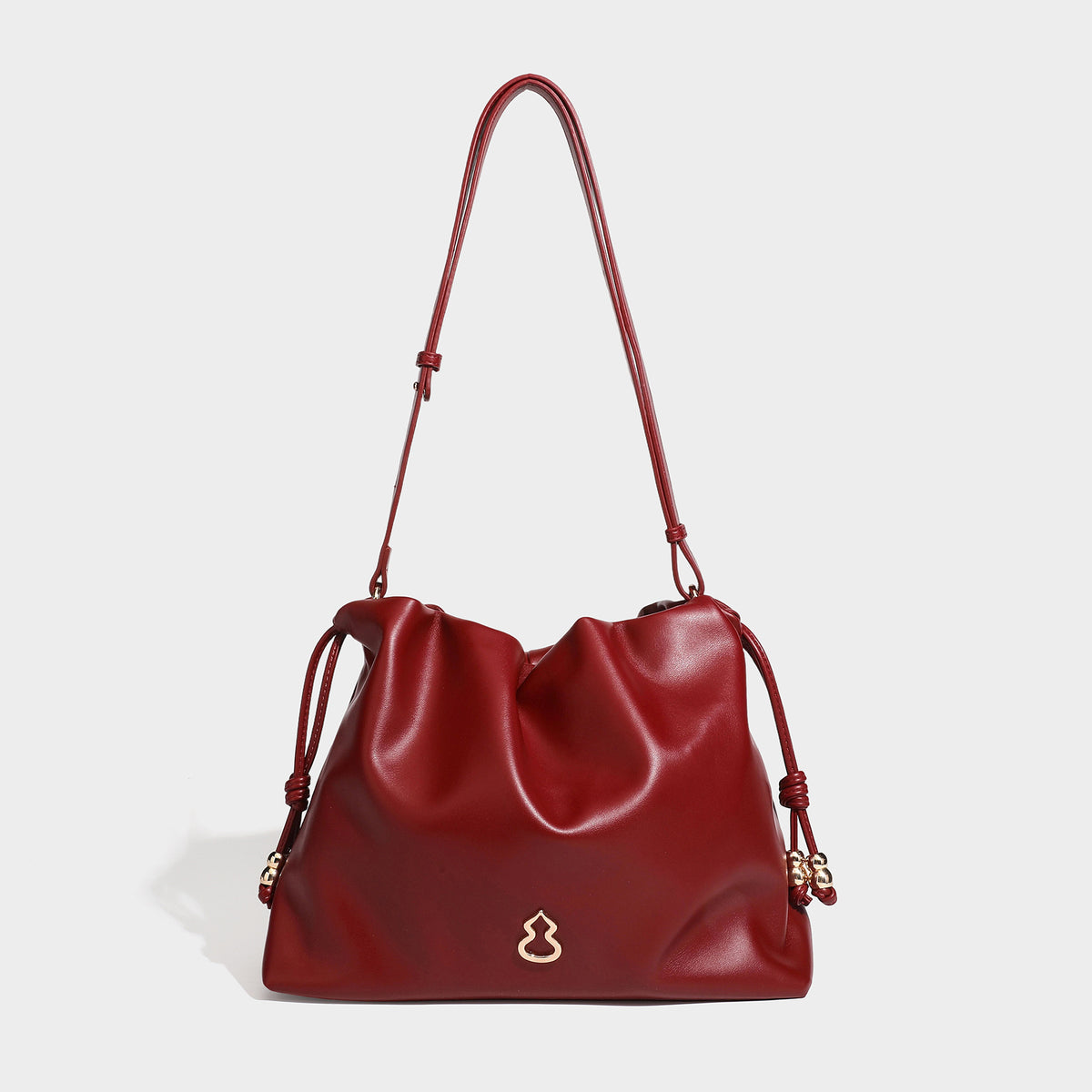 Slouchy ruched drawstring shoulder bag in smooth leather-look finish with gold-tone emblem and slim adjustable strap, detail