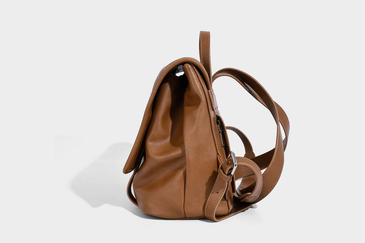 Structured tan leather-look flap backpack handbag with top handle, silver buckle hardware, and fold-over front closure