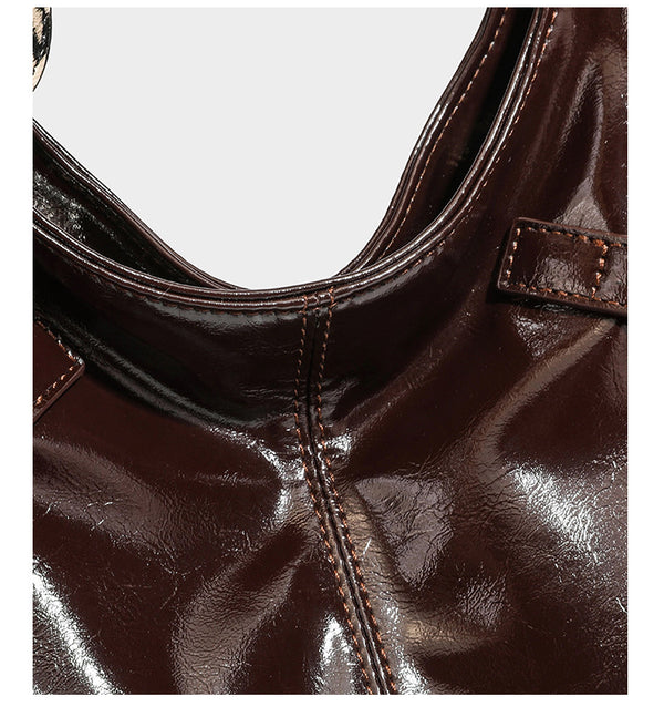 Glänzende, dunkelbraune Hobo-Schultertasche mit silberfarbenen Ösen am Riemen, vorderer Reißverschlusstasche und Herzmotiv im Leopardenprint