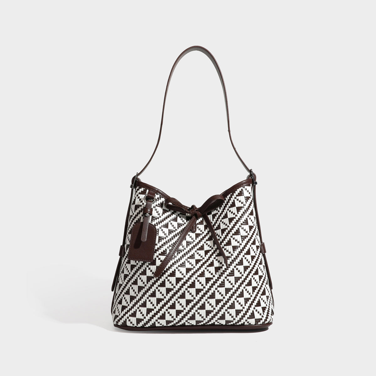Woven geometric bucket shoulder bag in white and dark brown two-tone pattern with leather-look trim and drawstring top