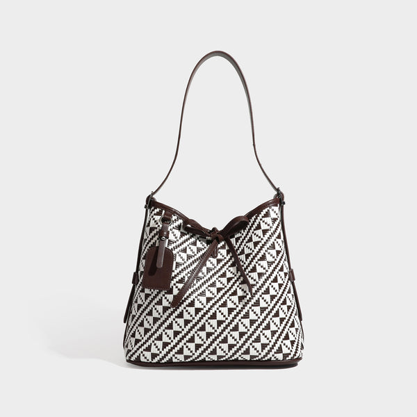 Woven geometric bucket shoulder bag in white and dark brown two-tone pattern with leather-look trim and drawstring top