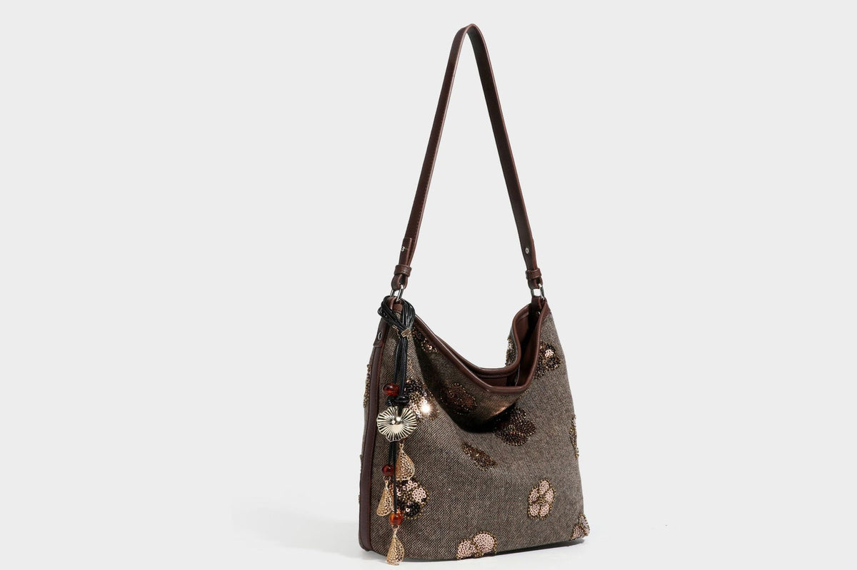 Lässig fallende Hobo-Schultertasche aus anthrazitfarbenem Webstoff mit floraler Stickerei aus silberfarbenen Pailletten, schwarzem Besatz in Lederoptik und langem