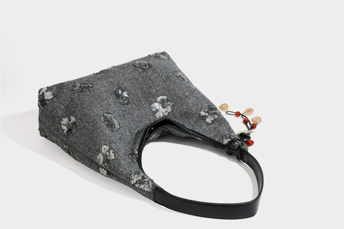 Lässig fallende, trapezförmige Schulter-Tote in Anthrazitgrau mit floralen Paillettenmotiven in Silber, Riemen in Lederoptik und herabhängendem Perlenbesatz