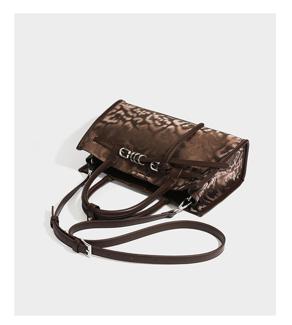 Structured leopard-print tote bag with glossy satin-like finish, dual rounded top handles, silver buckle-and-ring front