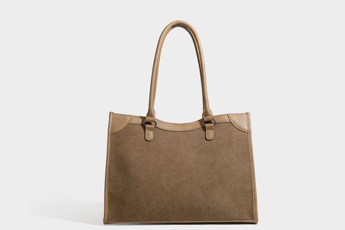 Large structured tote bag with matte suede-like body, smooth leather-look trim, front zip pocket, stud hardware, and