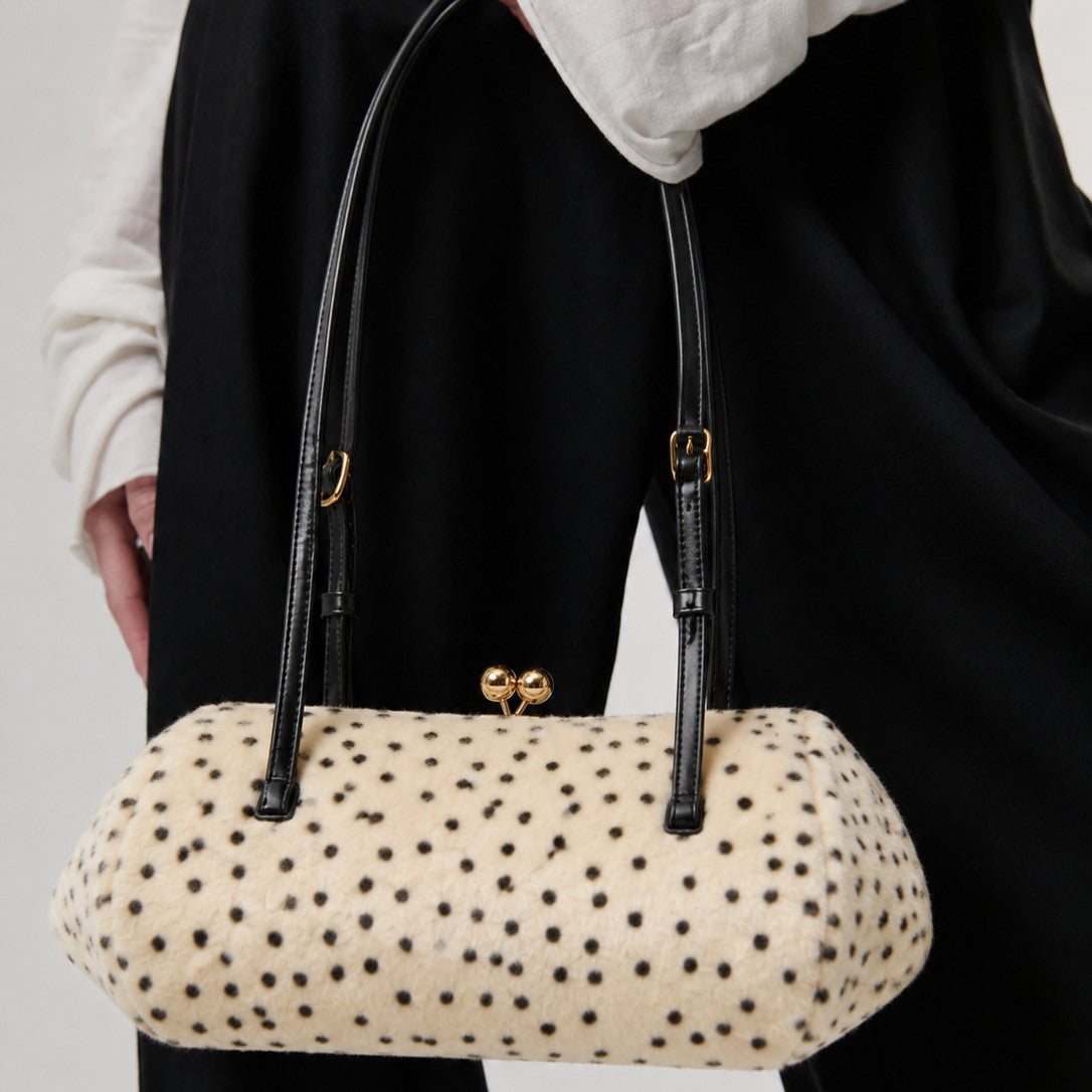 Spotted faux-fur barrel shoulder bag with gold kiss-lock clasp and black adjustable leather-look straps, front view