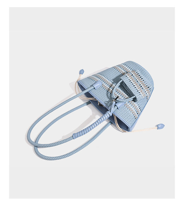 Light blue open-weave woven bucket tote bag with long braided shoulder straps, drawstring side ties, and attached mini pouch