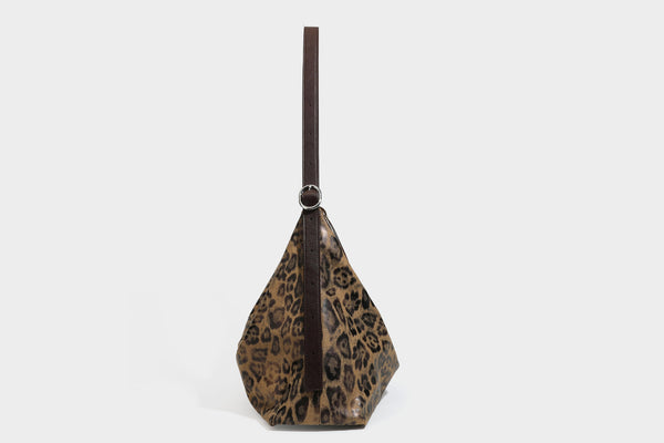 Slouchy leopard print hobo shoulder bag with glossy coated finish, top zipper closure, dark brown trim, and dangling charm