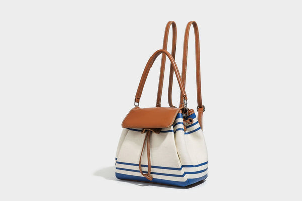Cream canvas bucket bag with blue horizontal stripes, tan leather-look flap and trim, drawstring closure, silver-tone, detail