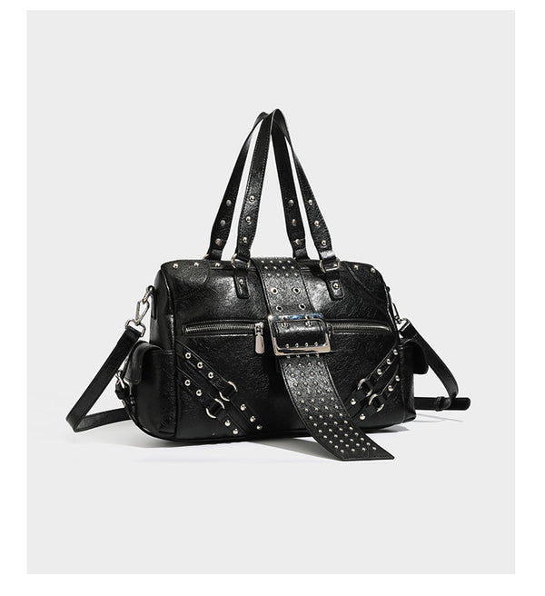 Structured pink leather-look satchel bag with gunmetal studded trim, rectangular buckle strap, dual top handles, and, detail