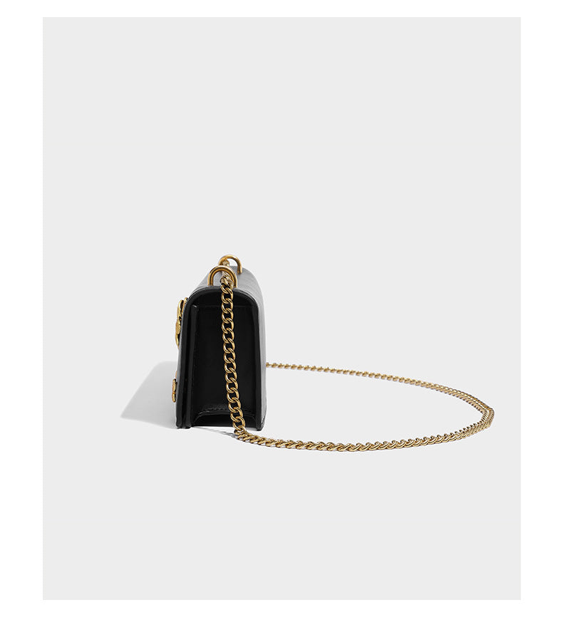 Slim rectangular crossbody bag with gold-tone butterfly metal appliqués and fine antiqued chain strap, detail view 9