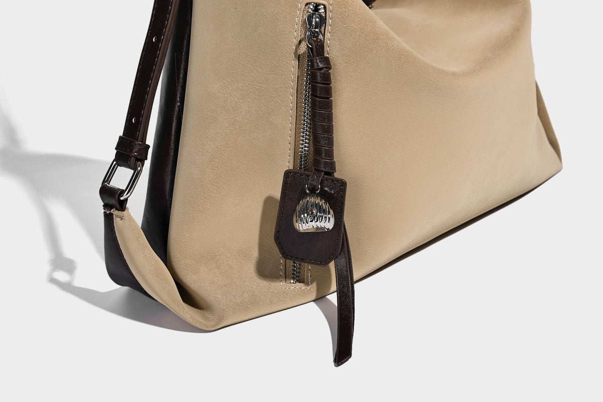Slouchy hobo tote bag with matte leather-look finish, triangular silhouette, front zip pocket, and adjustable shoulder strap