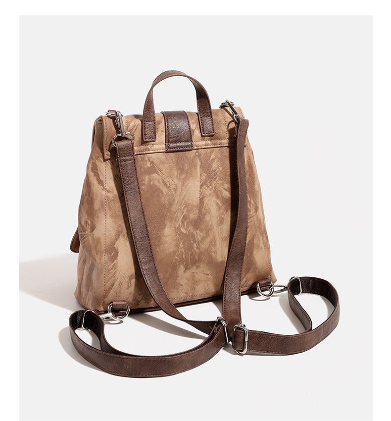 Compact distressed leather-look tan-brown backpack handbag with flap-and-buckle closure, two front patch pockets, top handle