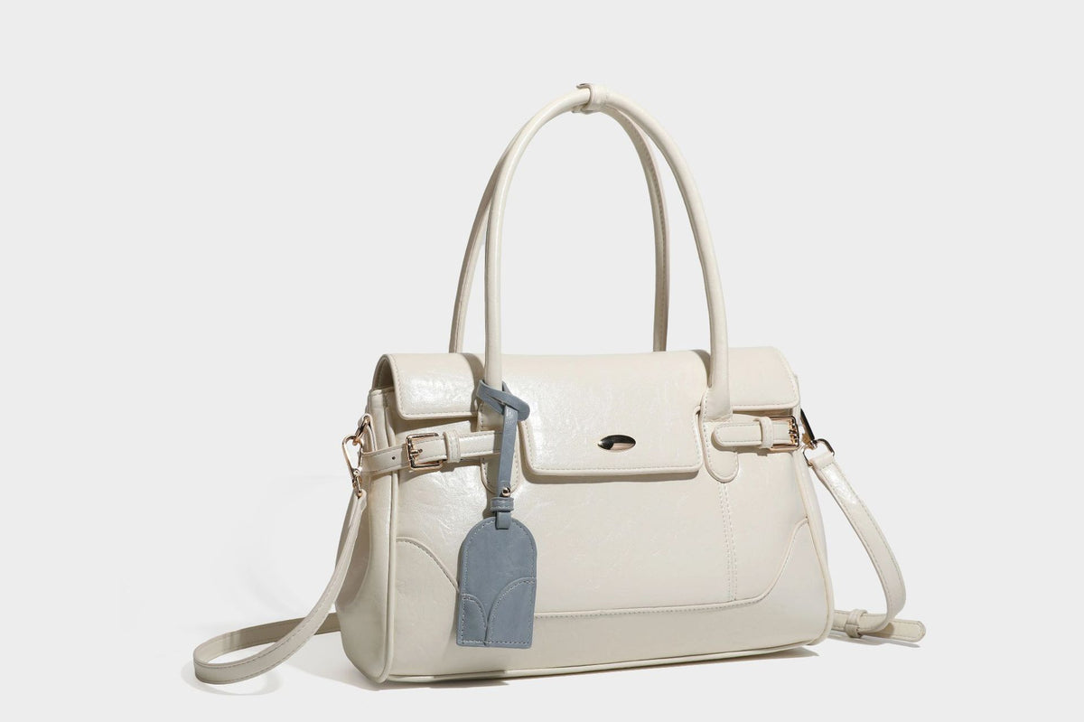 Structured glossy leather-look satchel bag with flap closure, gold-tone buckle accents, double top handles, detachable