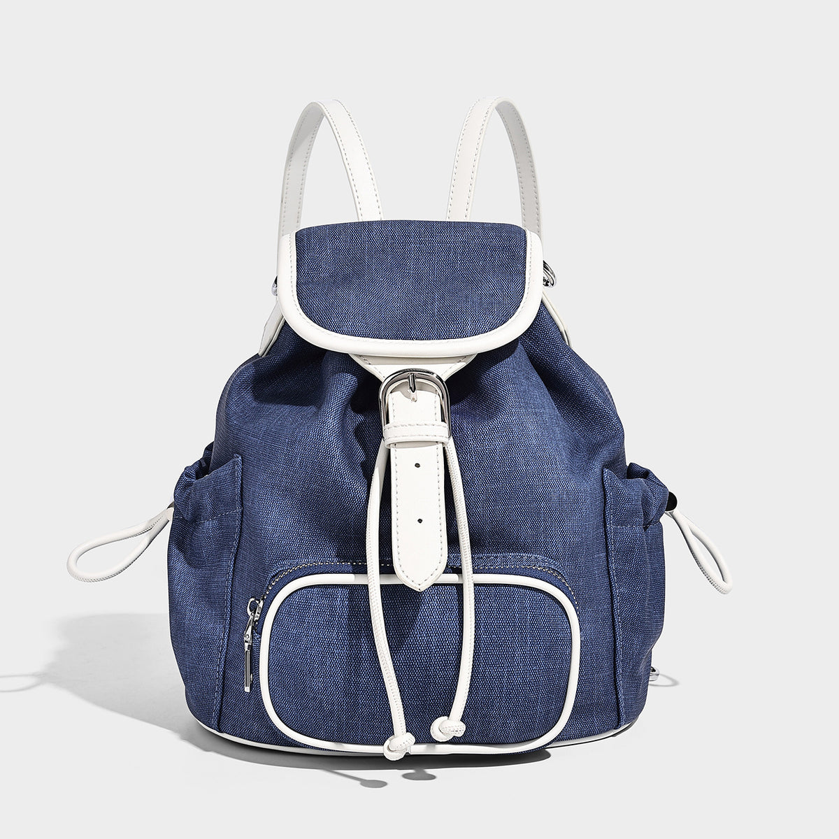 Compact denim drawstring backpack with white leather-look piping, flap-top buckle closure, front zip pocket, and silver-tone